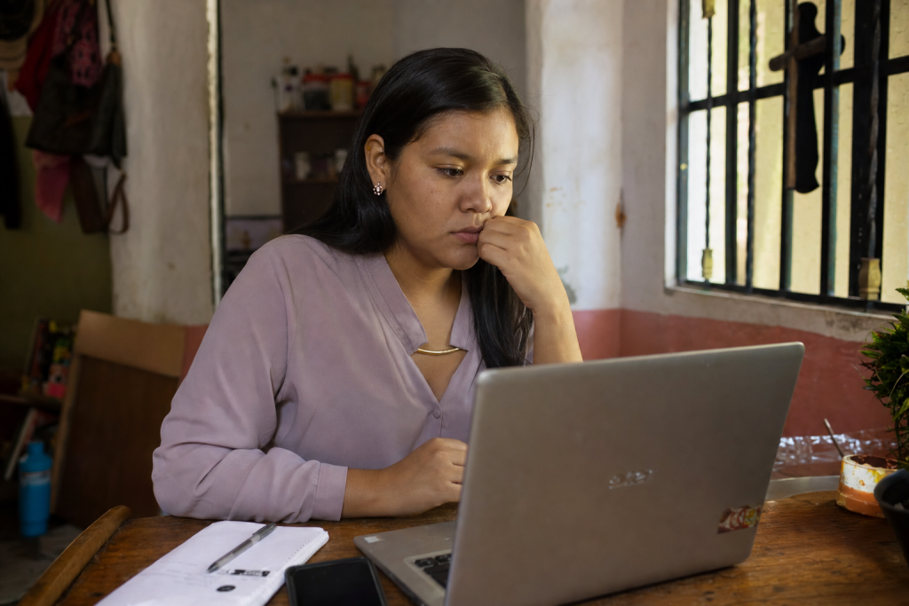 Young professional carefully reviewing a suspicious job offer on a laptop in a home office setting